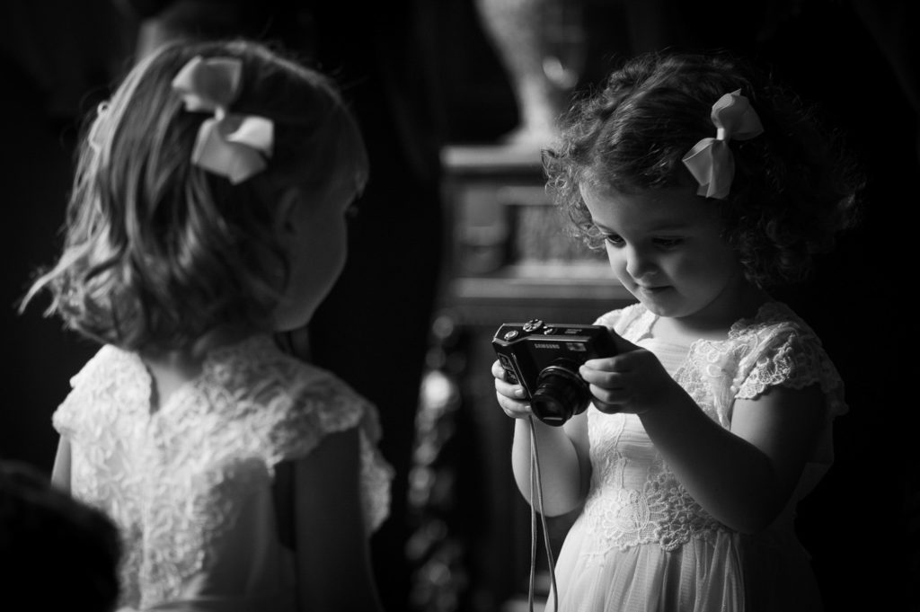 Flower girl examining a picture she has just taken on a camera of a second flower girl stood with her