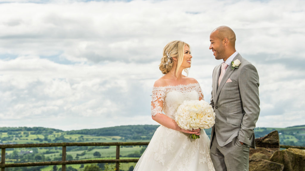Bride and groom looking and laughing at each each with beautiful countryside in the background