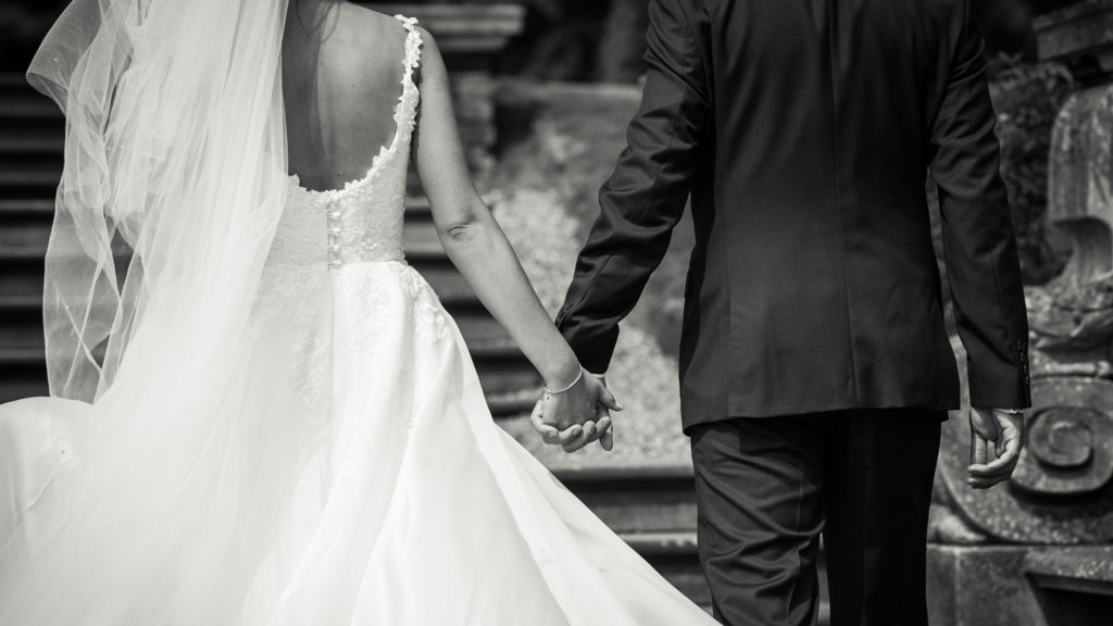 Bride and groom walking away from camera hand in hand