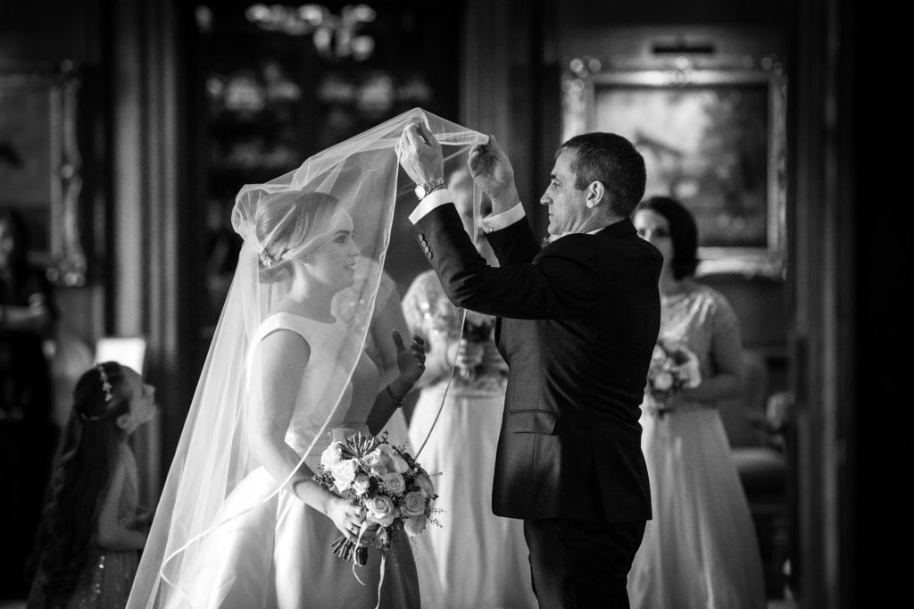 Father of the bride lifting his daughter's veil over her head just before entering ceremony at Knowsley Hall