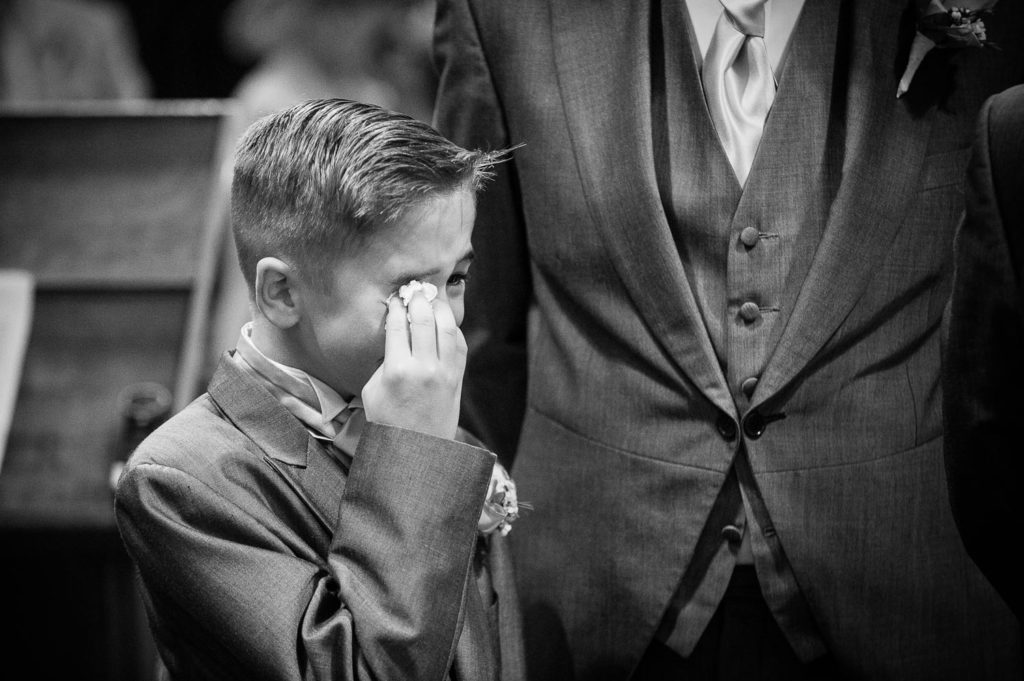 Bride and groom's young son as Best man in full Morning Suit wiping tears of joy from his eyes