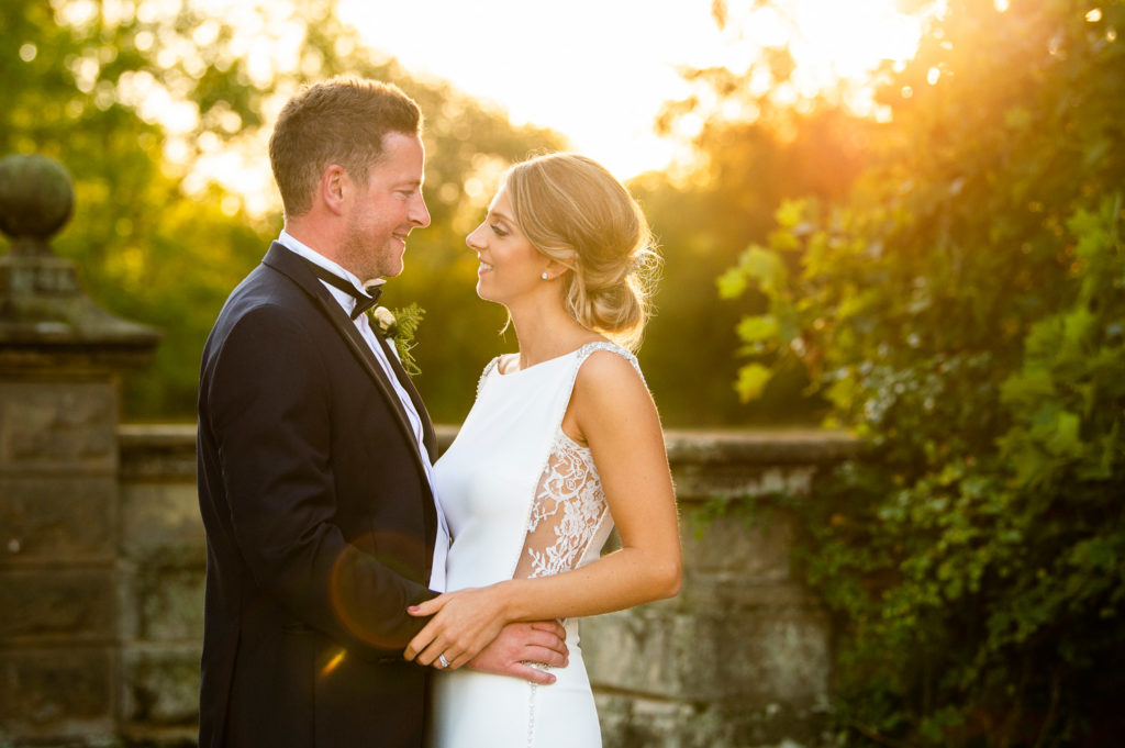 Early evening golden glow behind newlyweds in the garden at Iscoyd Park