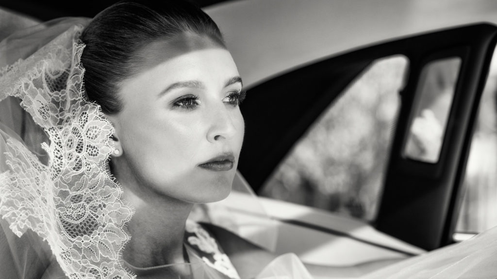 Bride captured in a reflective moment waiting in bridal car before ceremony