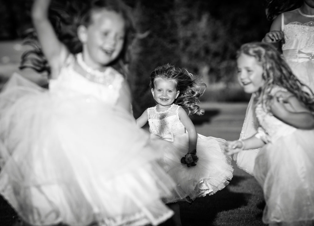 Young Flower girls in white dresses running and laughing in the gardens