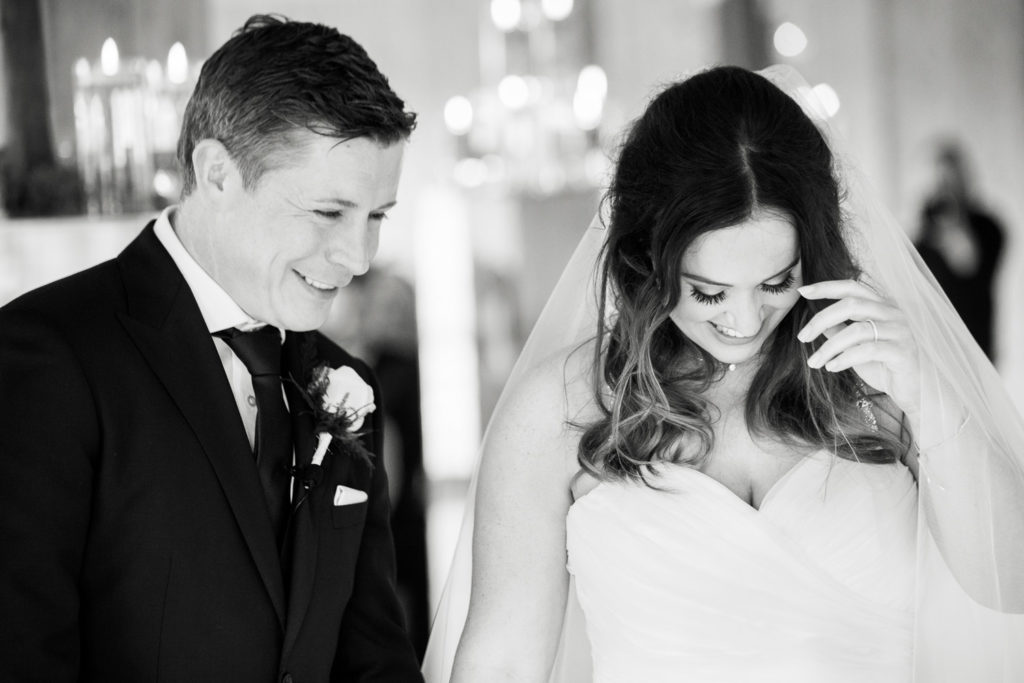 Bride and Groom looking down and laughing during wedding vows exchange in black and white