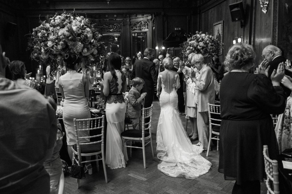 Newlyweds being received into their wedding breakfast weaving graciously through the tables