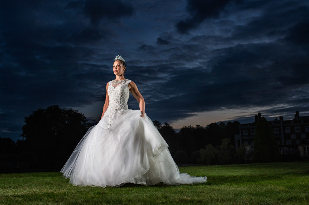 Dramatic dark blue night sky with bride face forward lifting her dress