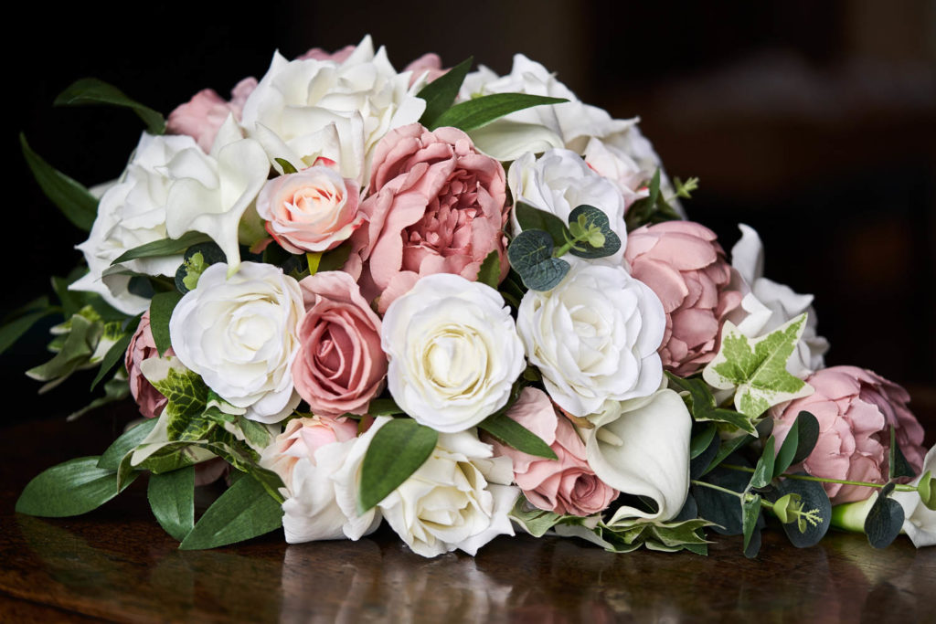 White and dusky pink blooms of peonies and roses in a teardrop bouquet
