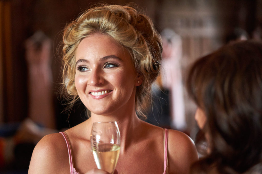 Beaming smile on a bridesmaid as she takes her glass of Champagne