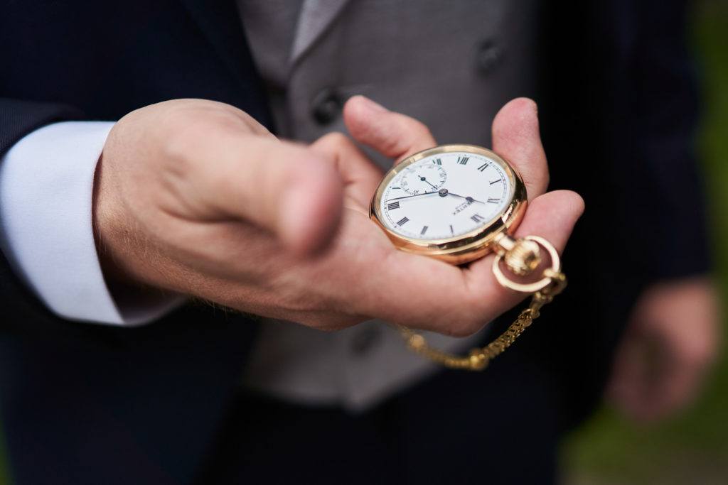 Close up detail of Groom's gold pocket watch before the ceremony showing 11:25am
