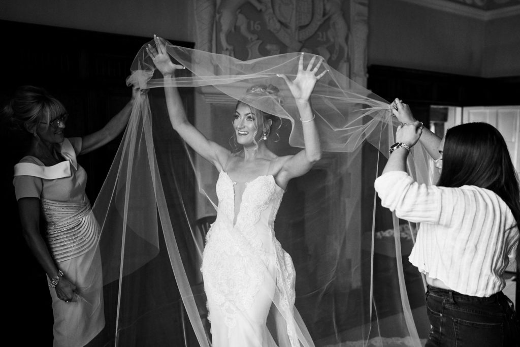 Veil being draped over bride's head before securing with her mum and hairdresser