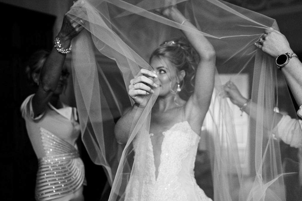 Bride adjusting length of her veil over her head