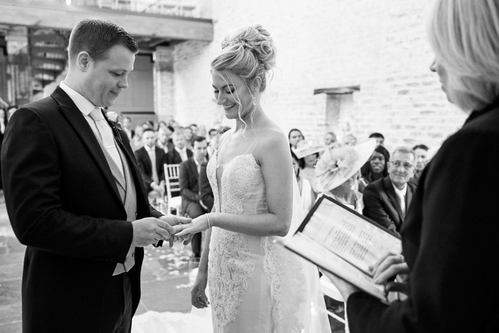 Groom placing the wedding band on his bride's finger at Dorfold Hall
