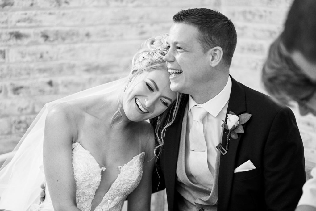 Bride nestling her head into groom's shoulder as they laugh together