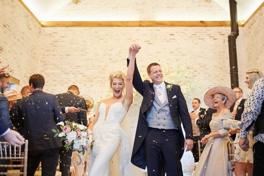Newlyweds holding hands as they punch the air laughing having been declared man and wife