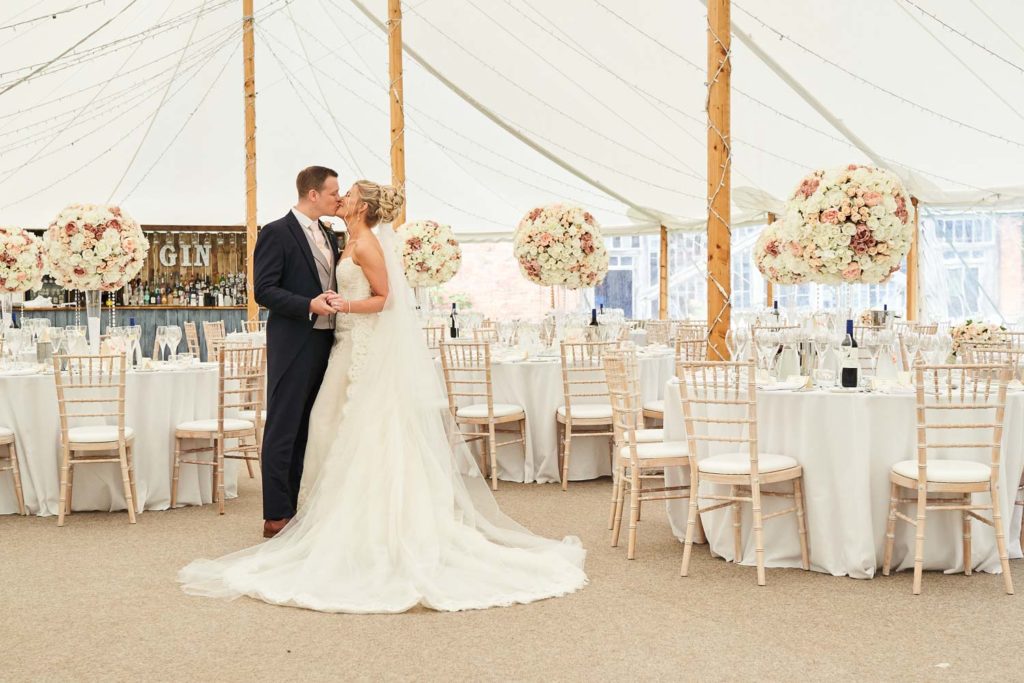 Bride and groom sharing a kiss in the marquee before guests arrive