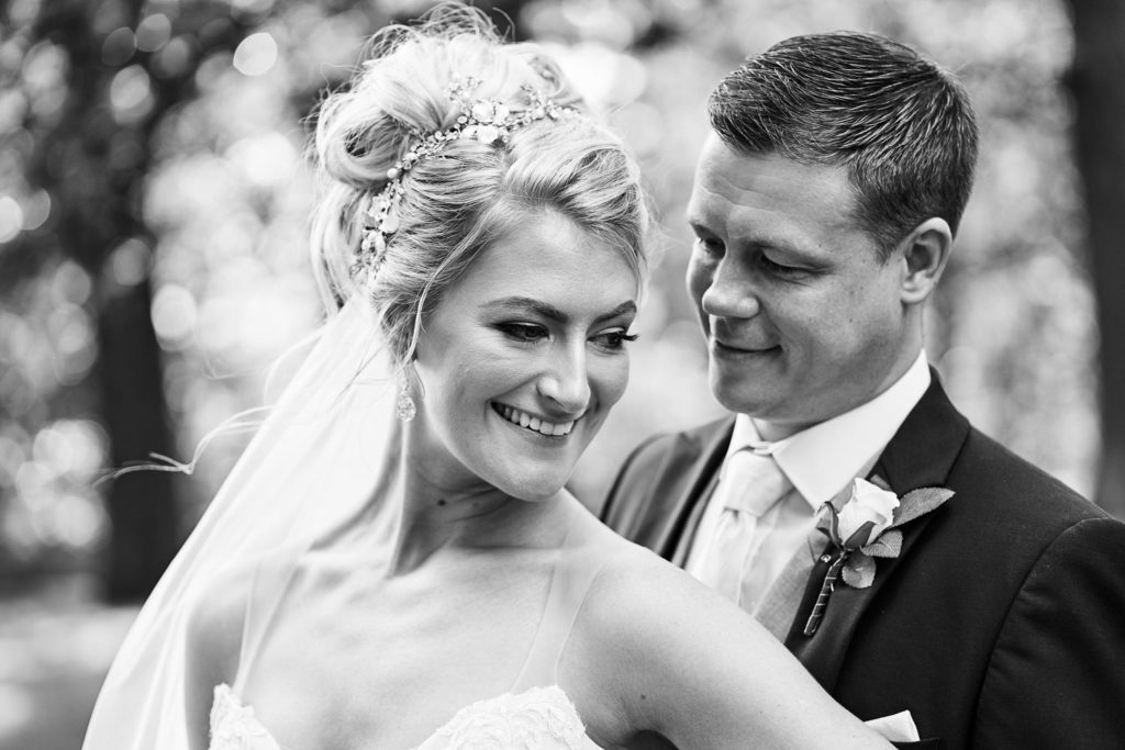 Close up as Bride stands with her back to her groom and glances back to him as he looks at his wife