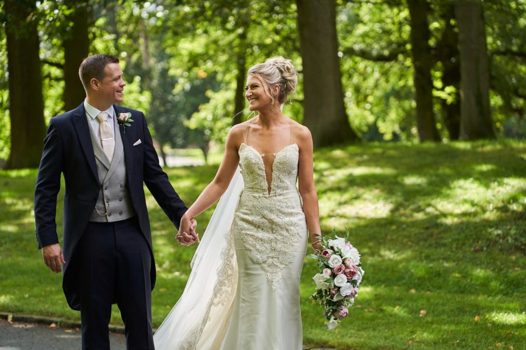 Happy couple walking through a wooded area holding hands and smiling at each other