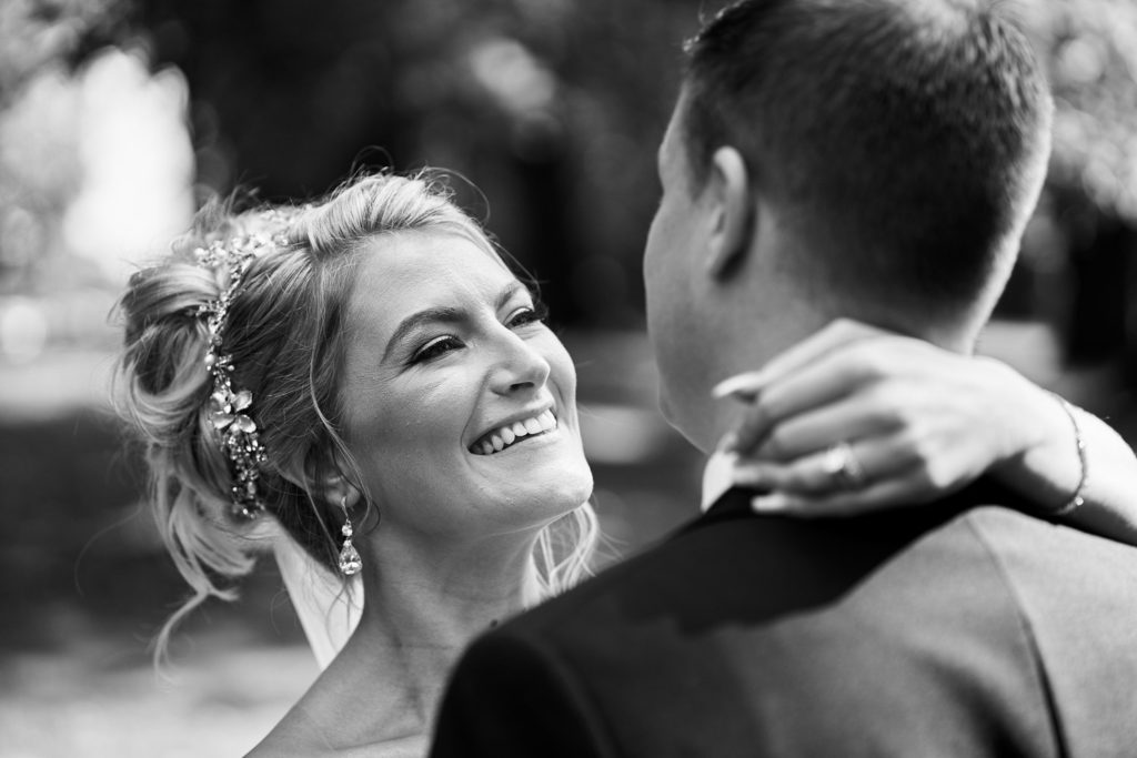 Bride looking full of love for her husband as she casually drapes her arm around his neck