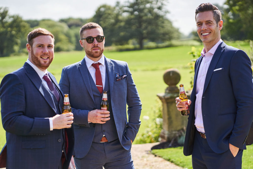 Male guests casually drinking beer and smiling in the gardens