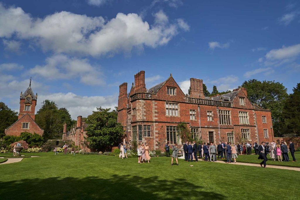 Dorfold Hall rear gardens with guests relaxing under blue skies
