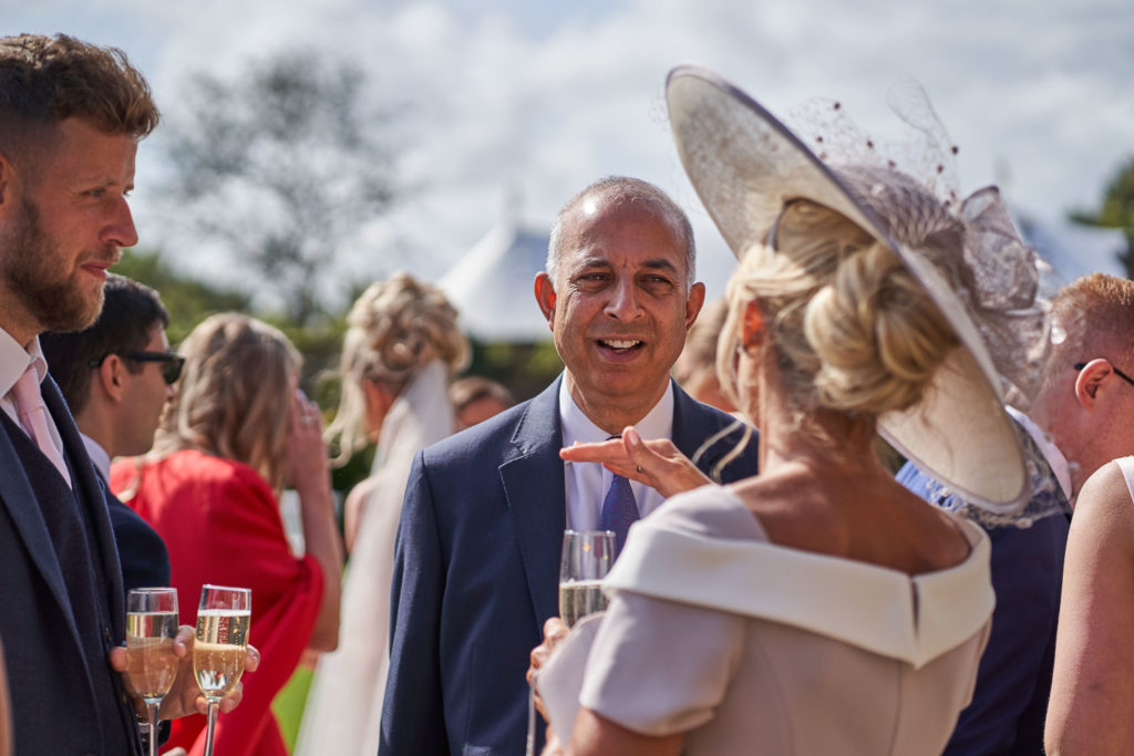 Mother of the bride chatting to family and friends with champagne in hand