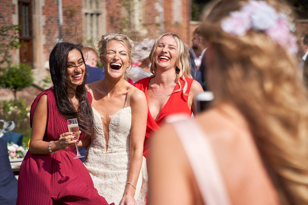 Bride and some friends posing in a picture for a guest as they all laugh