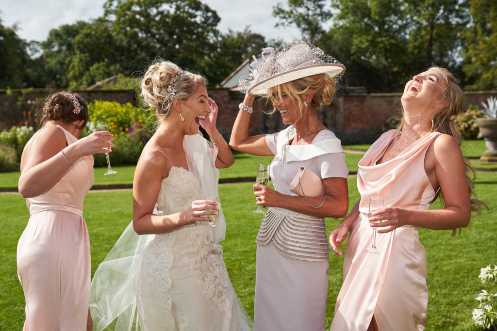 Bride and bridesmaids with Mother of the bride all laughing heartily in the gardens