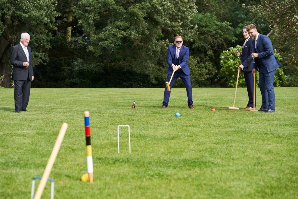With a beer on the floor beside him, an usher tries to hit his ball through the croquet hoop