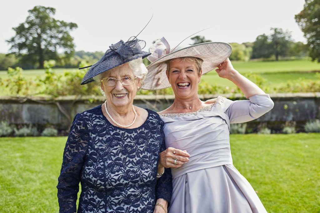 Two female guests wearing hats posing for a picture as a slight breeze arrives