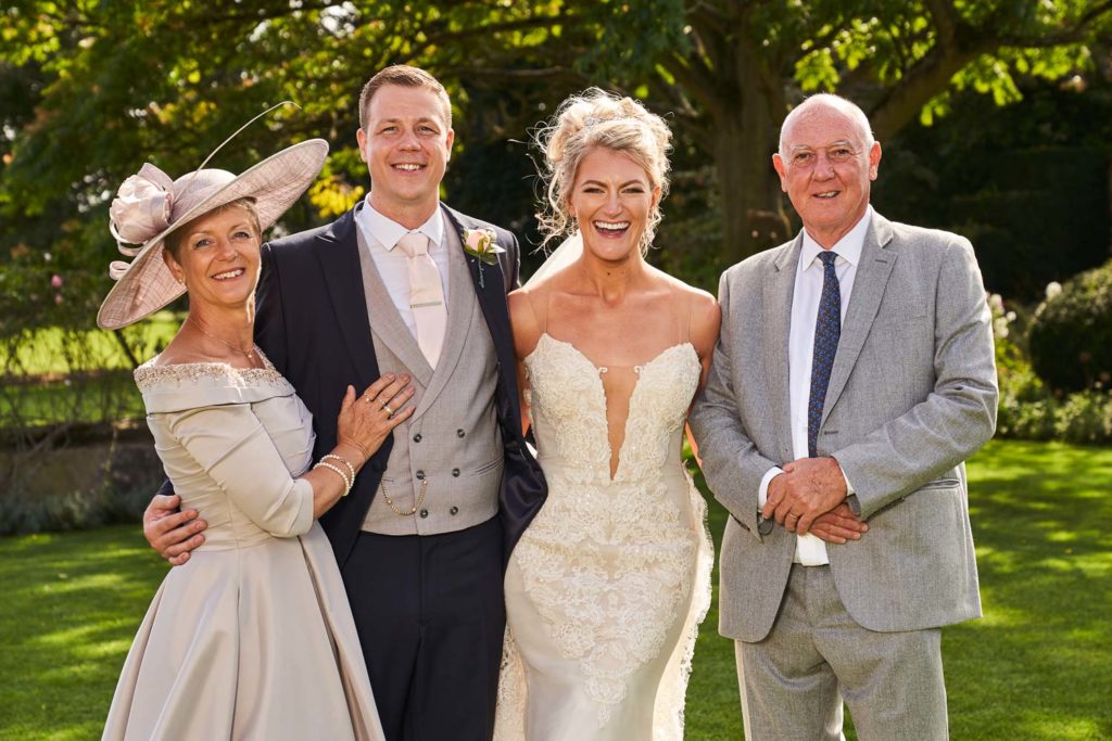 Bride and groom posed with his parents as they all laugh