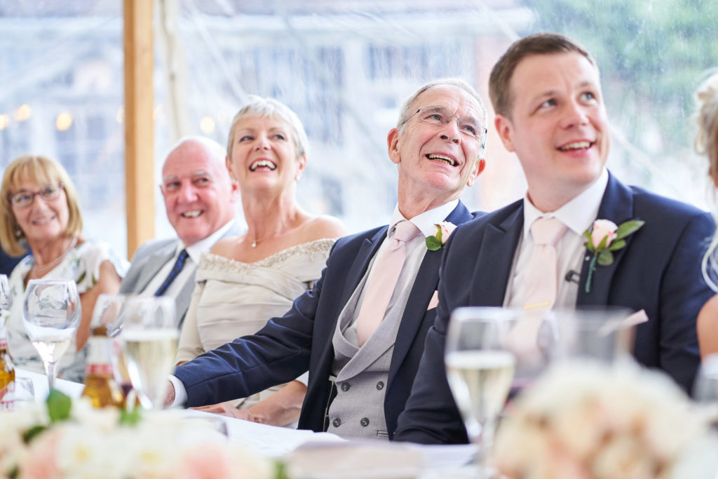 Top table featuring groom, laughing during speeches