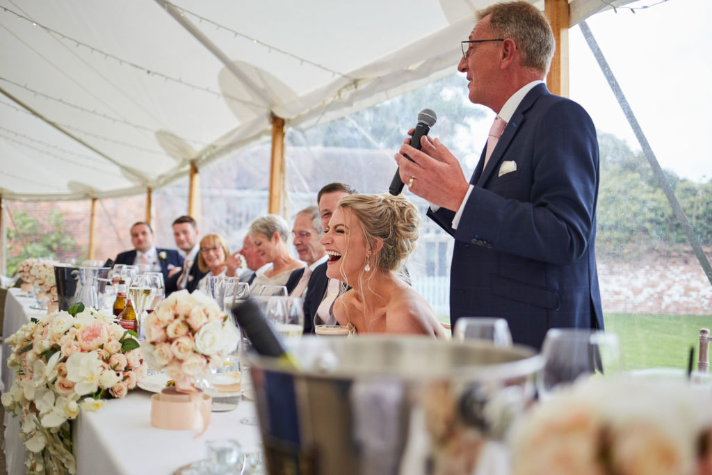 Bride laughing as her dad shares stories of her during his speech