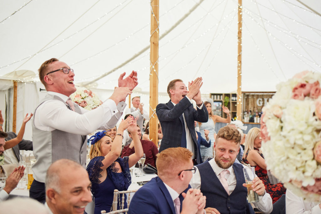 Guests on their feet cheering and clapping during Groom's speech