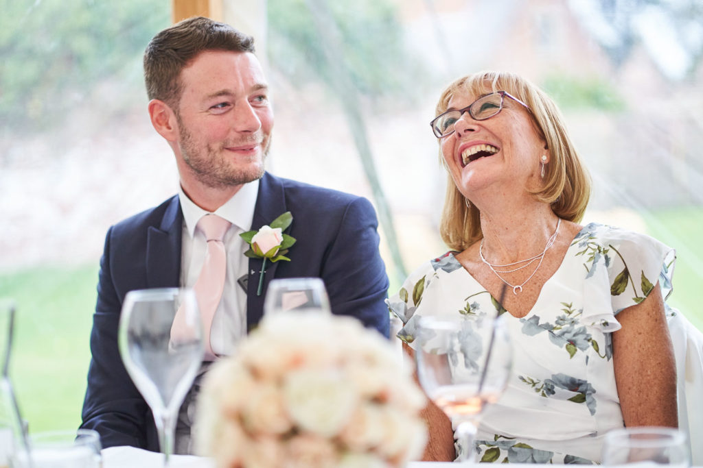 Mother of the groom laughing during her son's speech