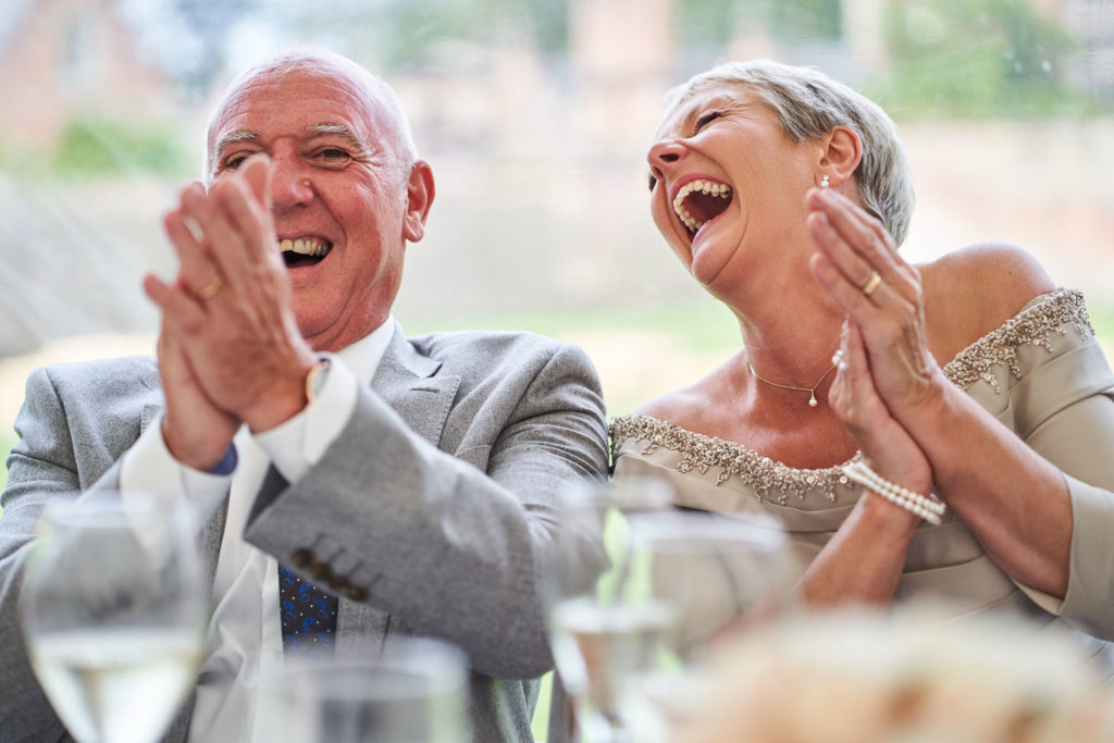 Parents of the newlyweds laughing uncontrollably as Groom gives his speech