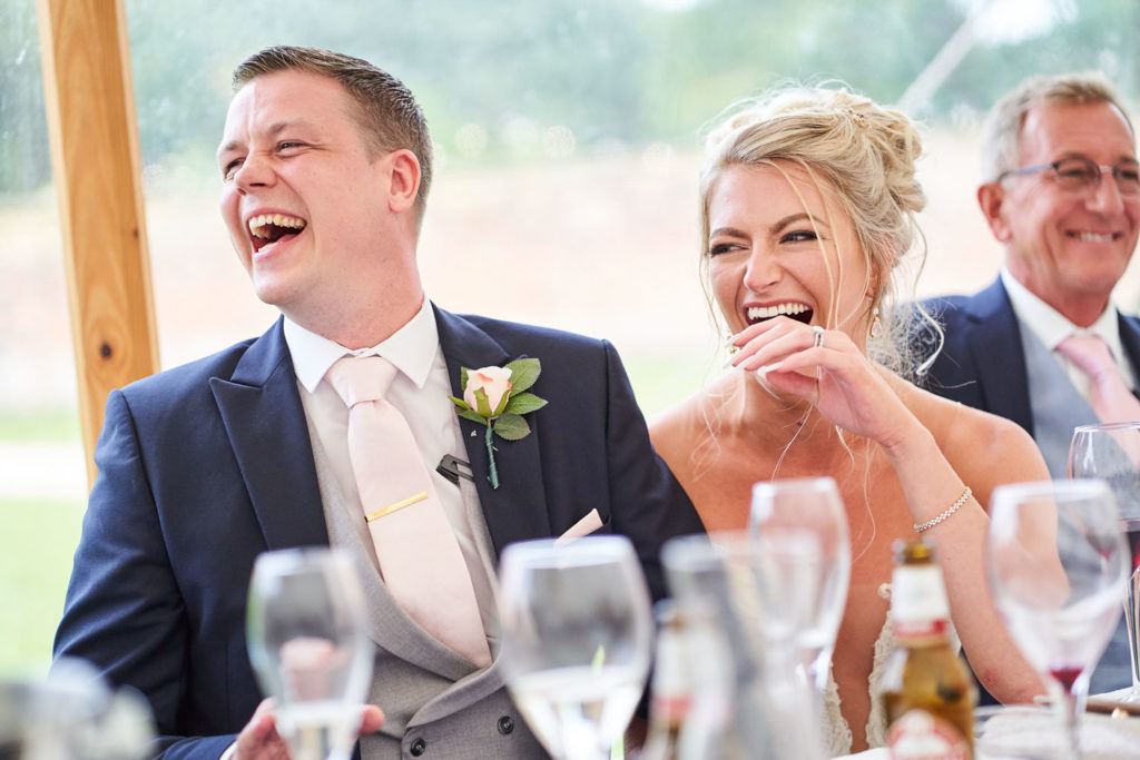 Happy couple sat laughing at Best Man's speech