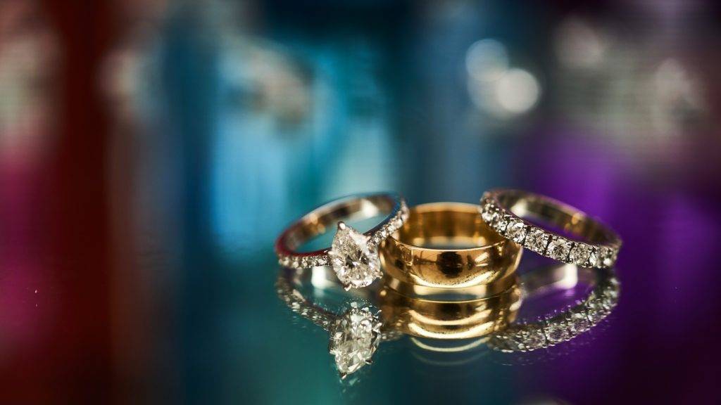 Reflected wedding rings feature with a backdrop of purples, blues and reds