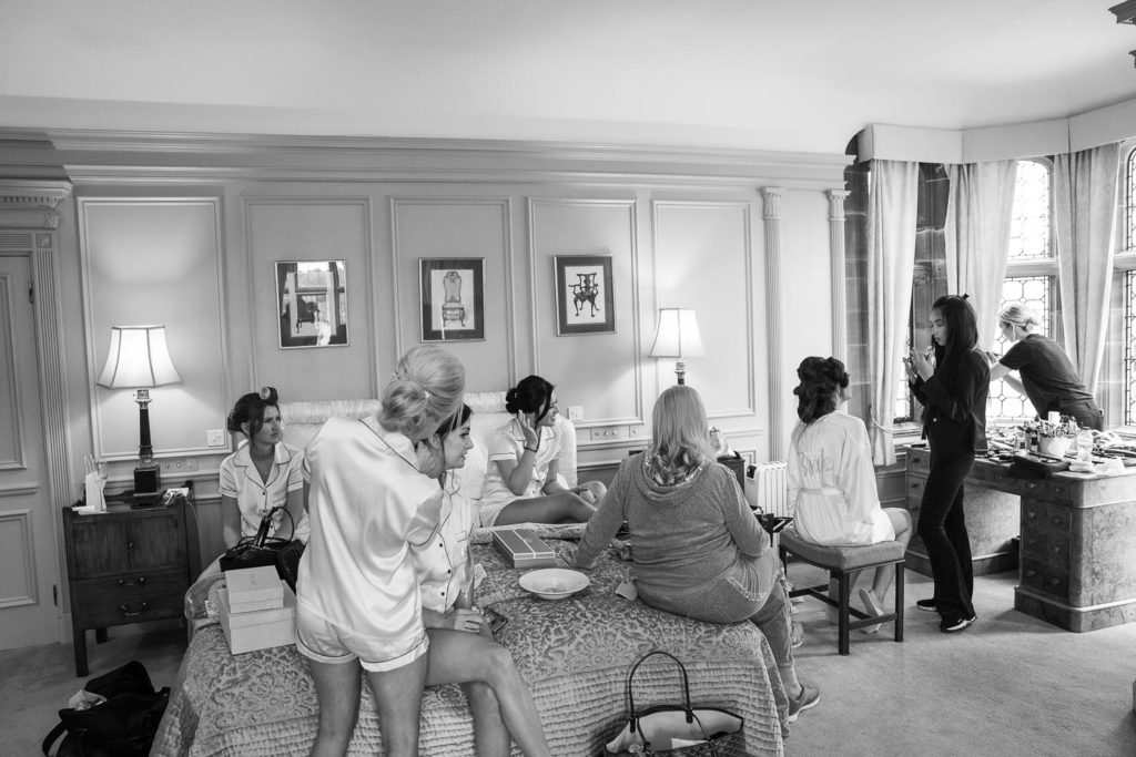 Bridesmaids sat around in shorts pyjamas as they watch bride having her makeup completed
