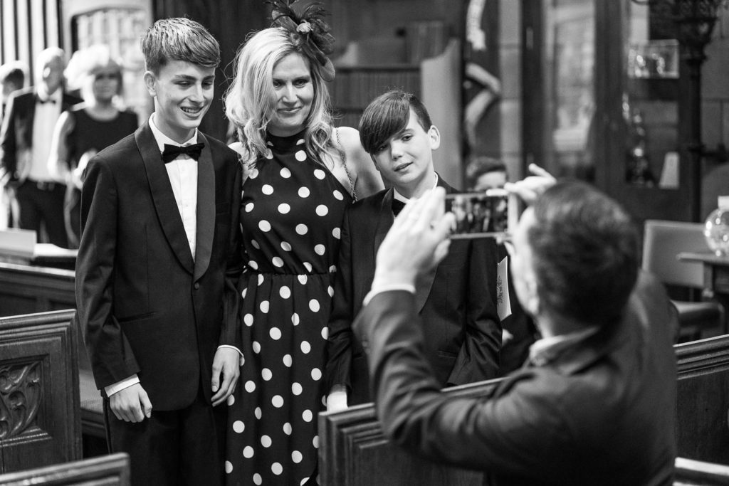 Guests comprising of mother and two sons posing for a mobile phone picture in church before the ceremony starts