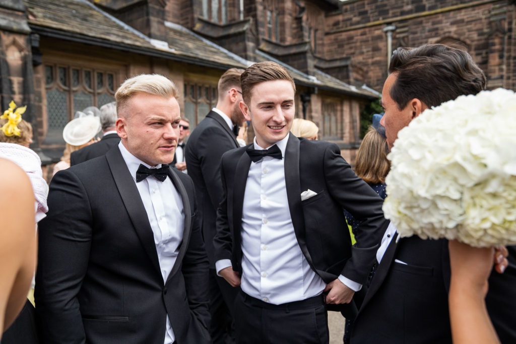 Groomsmen milling around outside the church after the wedding ceremony