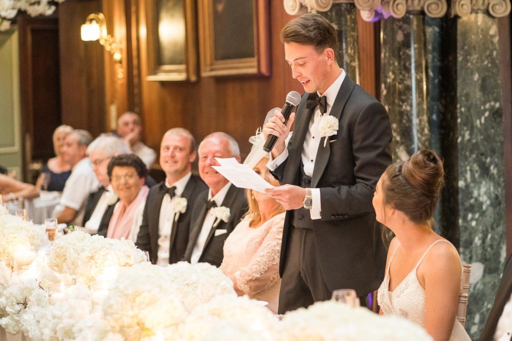Groom giving his speech as family and friends smile all around him