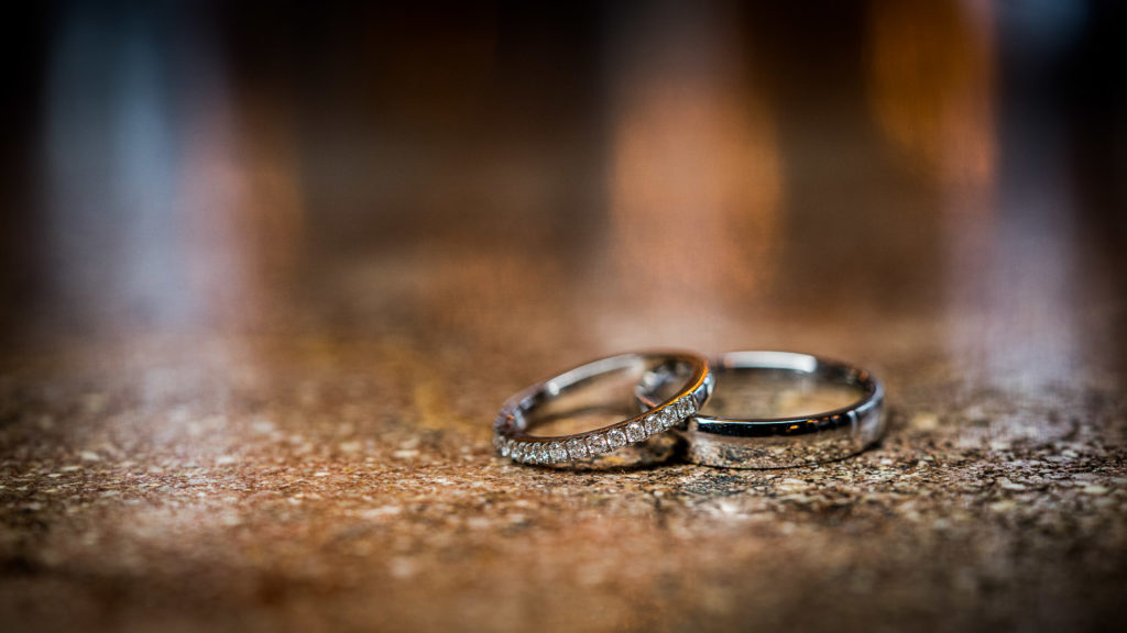 Wedding bands on a glittery surface with blurry lights behind them