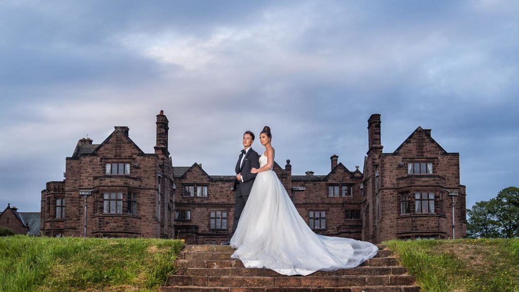 Bride groom stood on the steps in the rear garden with Thornton Manor behind them