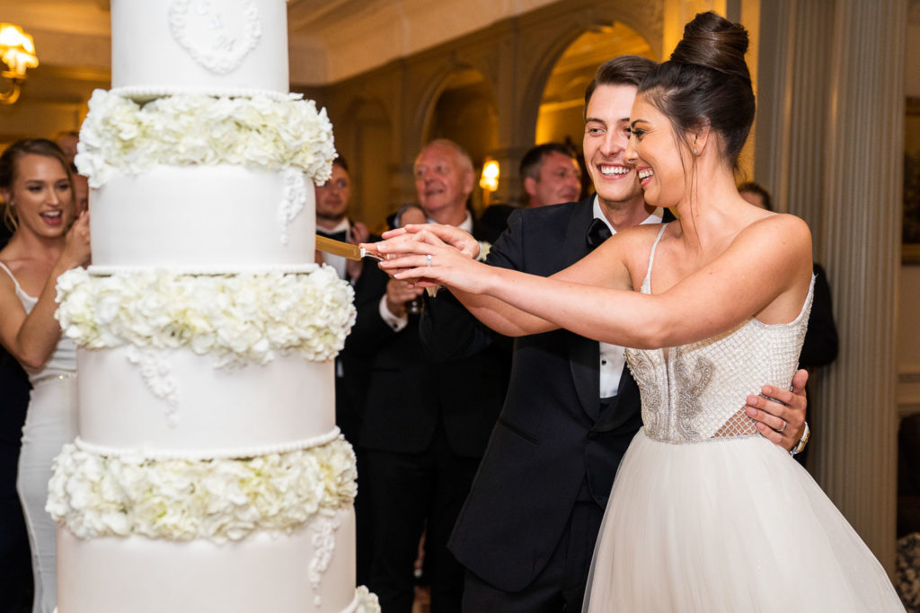 Bride and groom cutting their cake laughing with each other