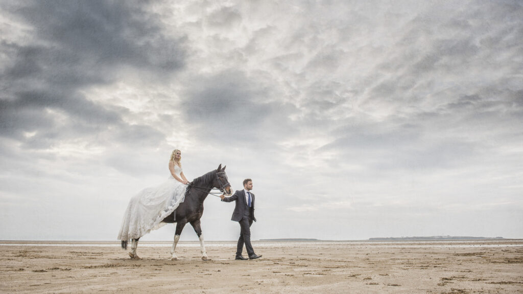 Bride on horseback riding on the beach.